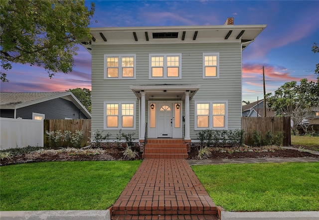 italianate house with a chimney, fence, and a yard