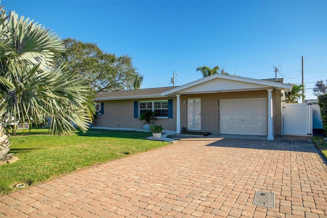 ranch-style house with decorative driveway, a gate, fence, a garage, and a front lawn