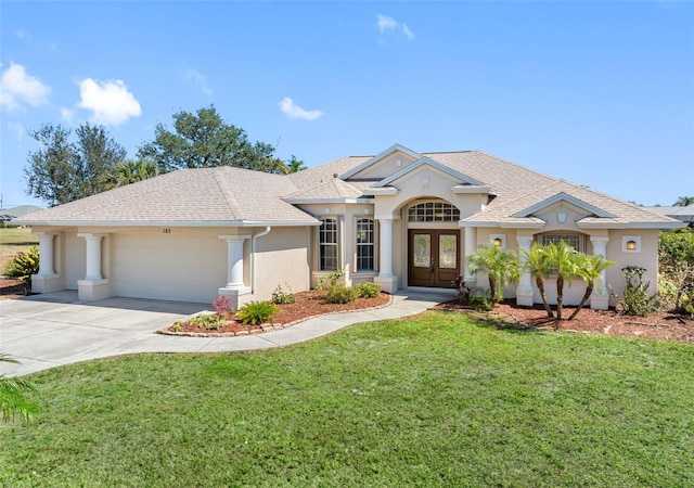 view of front of home featuring french doors, stucco siding, an attached garage, a front yard, and driveway