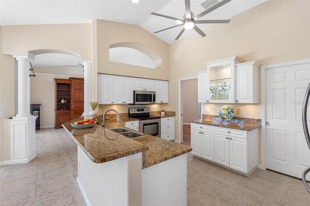 kitchen featuring ceiling fan, dark stone countertops, stainless steel appliances, ornate columns, and a sink