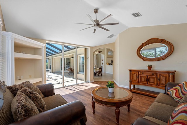 living area featuring arched walkways, lofted ceiling, visible vents, a ceiling fan, and wood finished floors