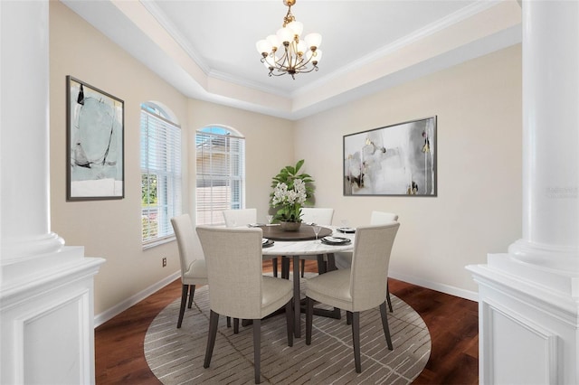 dining area featuring dark wood-type flooring, decorative columns, a raised ceiling, and a notable chandelier