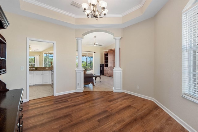 interior space with arched walkways, wood finished floors, visible vents, a raised ceiling, and decorative columns