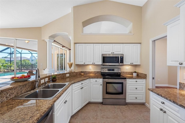 kitchen featuring decorative columns, a sunroom, stainless steel appliances, white cabinetry, and a sink