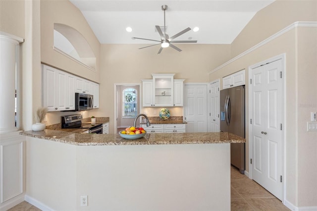 kitchen with stainless steel appliances, light stone counters, a peninsula, and light tile patterned flooring