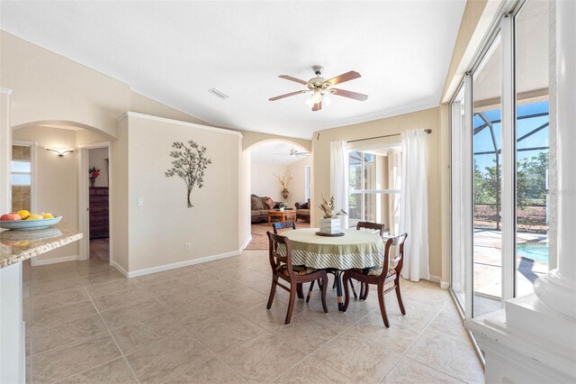 dining area featuring arched walkways, visible vents, a ceiling fan, vaulted ceiling, and baseboards