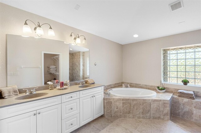 full bath featuring a garden tub, a sink, visible vents, and tile patterned floors