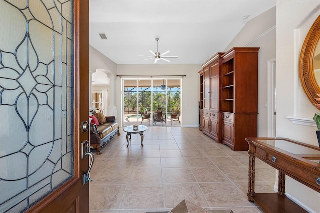 living area featuring lofted ceiling, light tile patterned floors, visible vents, a ceiling fan, and decorative columns