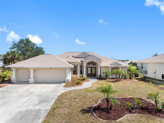 view of front facade with french doors, stucco siding, a front yard, a garage, and driveway