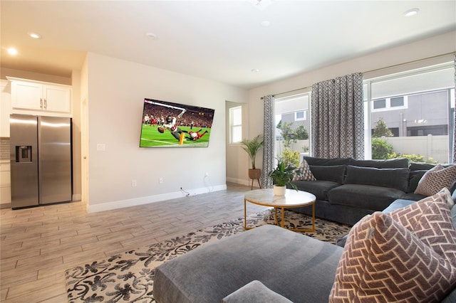 living area featuring light wood-style flooring, baseboards, and recessed lighting