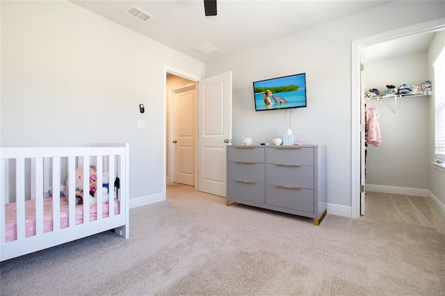 bedroom featuring a walk in closet, visible vents, light carpet, and baseboards