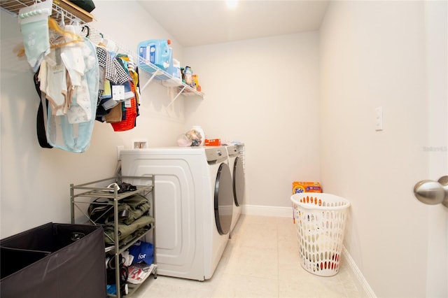 washroom featuring laundry area, baseboards, washer and dryer, and light tile patterned flooring