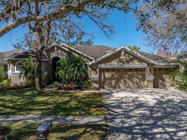 view of front of property featuring driveway, a front lawn, an attached garage, and stucco siding