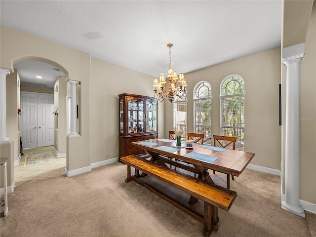 dining room featuring arched walkways, light colored carpet, baseboards, decorative columns, and an inviting chandelier