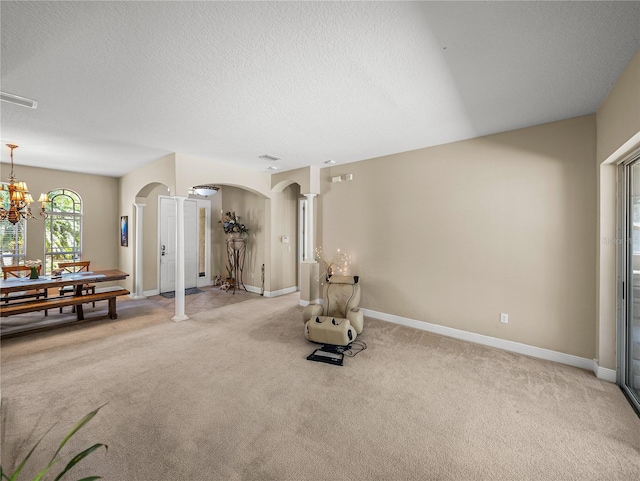 sitting room featuring arched walkways, a textured ceiling, a chandelier, light colored carpet, and visible vents