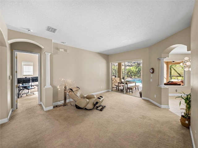 sitting room with light colored carpet, decorative columns, visible vents, and a textured ceiling