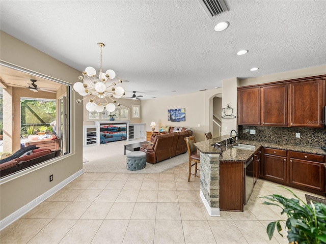 kitchen featuring arched walkways, a peninsula, a sink, open floor plan, and decorative backsplash