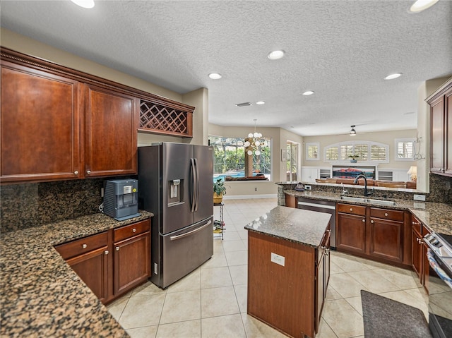 kitchen with stainless steel appliances, open floor plan, a sink, and light tile patterned floors