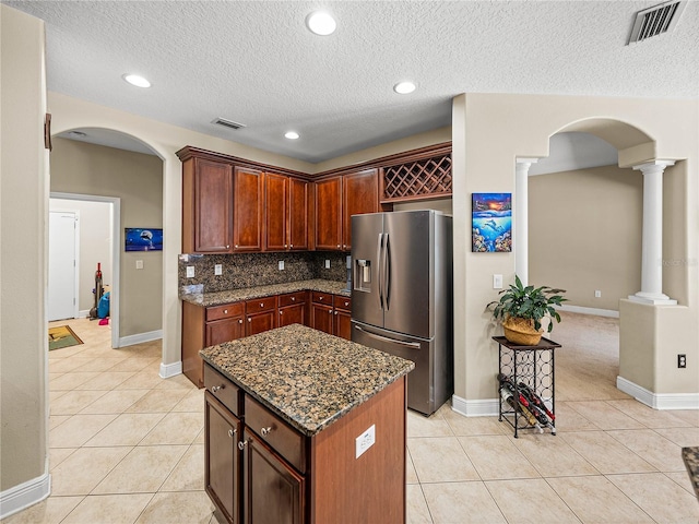 kitchen with light tile patterned floors, stainless steel refrigerator with ice dispenser, arched walkways, and ornate columns