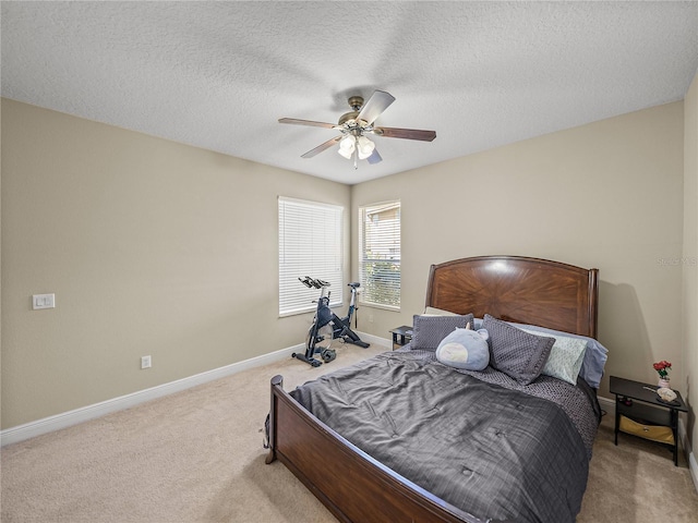 bedroom with ceiling fan, a textured ceiling, baseboards, and carpet flooring