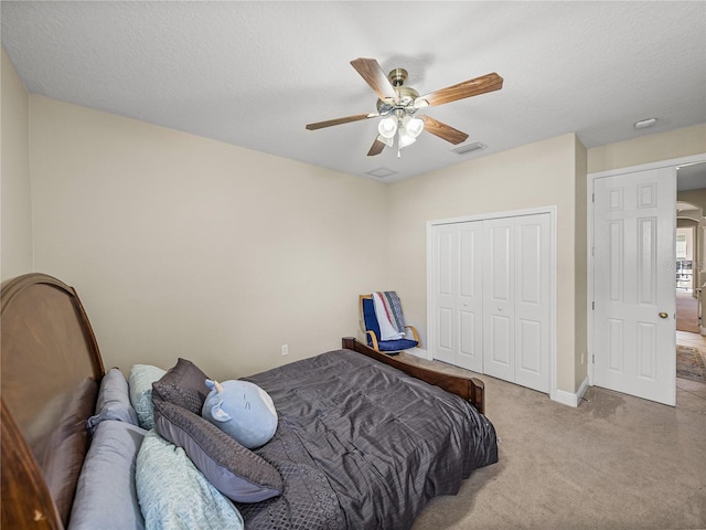 carpeted bedroom featuring baseboards, visible vents, a ceiling fan, a textured ceiling, and a closet