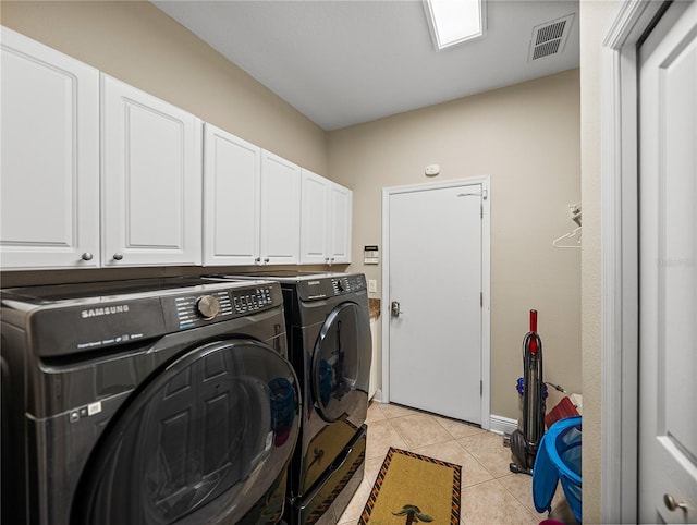 laundry room featuring cabinet space, washing machine and dryer, visible vents, and light tile patterned flooring