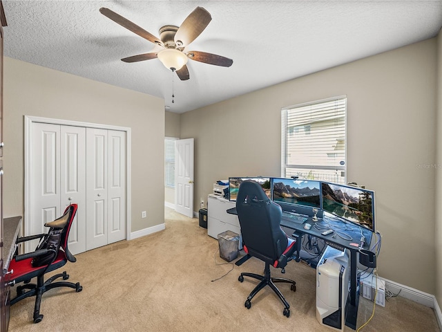 carpeted office space featuring a ceiling fan, a textured ceiling, and baseboards