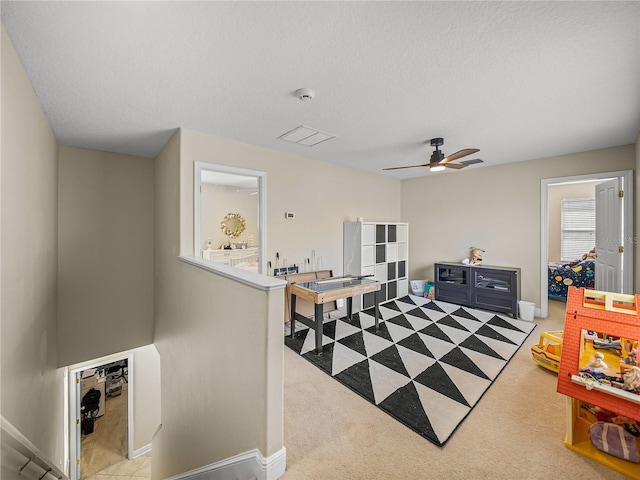 interior space with carpet floors, a ceiling fan, baseboards, and a textured ceiling