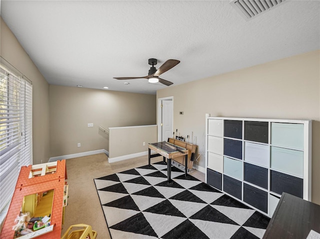 recreation room featuring visible vents, ceiling fan, a textured ceiling, and baseboards