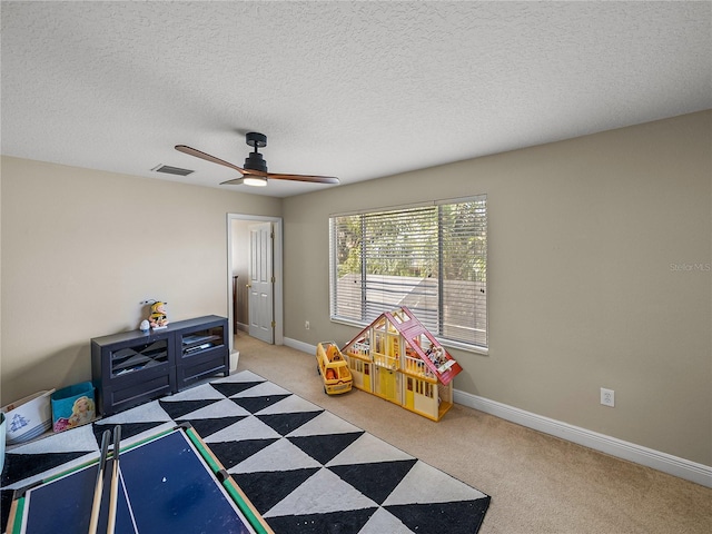 rec room with ceiling fan, a textured ceiling, light carpet, visible vents, and baseboards