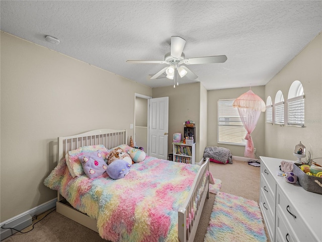 bedroom featuring baseboards, a textured ceiling, a ceiling fan, and light colored carpet