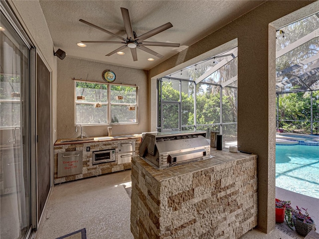 sunroom / solarium featuring ceiling fan and a sink