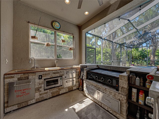 sunroom / solarium featuring lofted ceiling, a sink, and ceiling fan