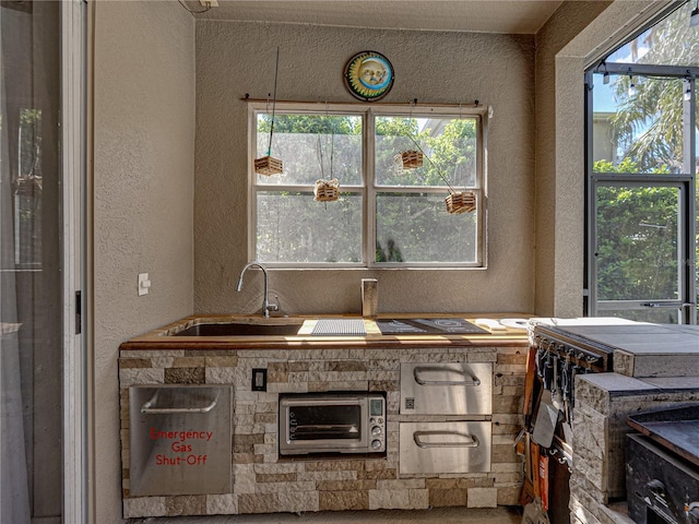 kitchen featuring a textured wall and a sink