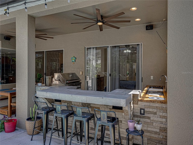 view of patio / terrace with a sink, ceiling fan, exterior kitchen, and area for grilling