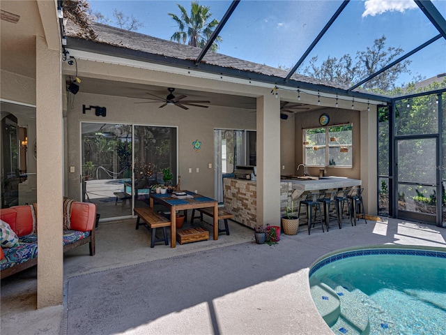 pool featuring a patio area, glass enclosure, and outdoor dry bar