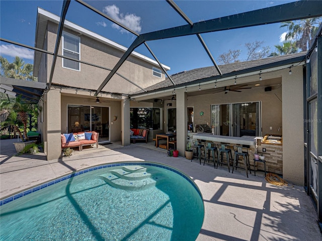 back of house featuring stucco siding, outdoor lounge area, a patio area, a lanai, and an outdoor pool