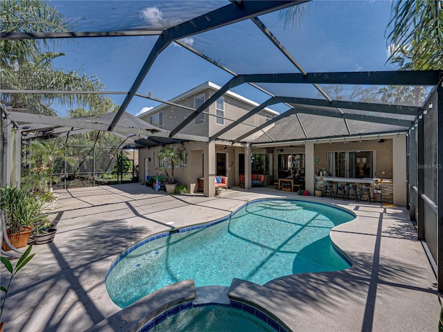 view of swimming pool with a pool with connected hot tub, a patio, outdoor dry bar, and a lanai