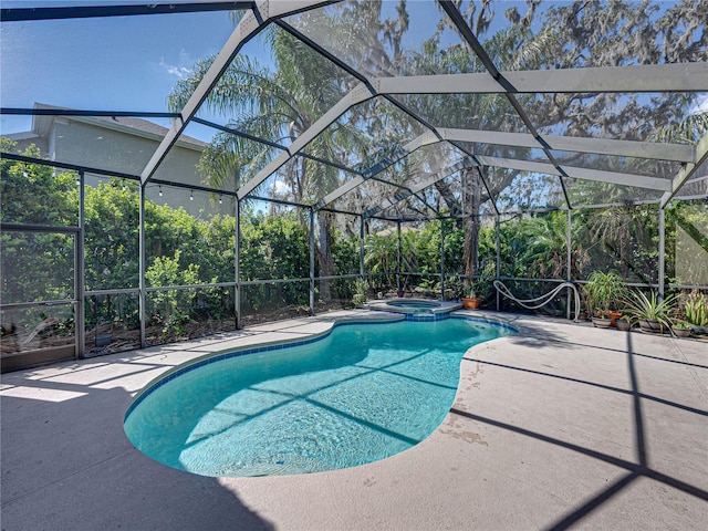 view of pool featuring glass enclosure, a pool with connected hot tub, and a patio area