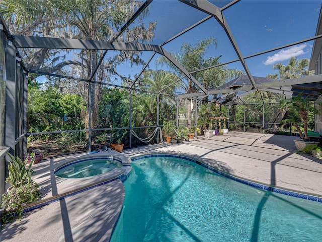 view of swimming pool featuring glass enclosure, a patio area, and a pool with connected hot tub