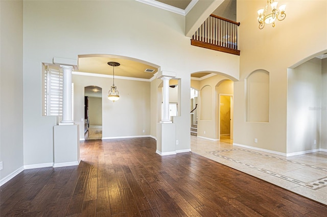 unfurnished room featuring a towering ceiling, wood-type flooring, baseboards, and crown molding