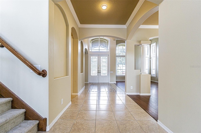 entryway with french doors, arched walkways, crown molding, and light tile patterned flooring