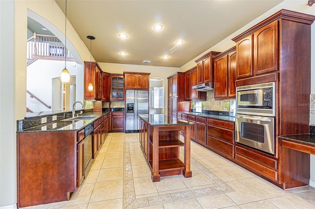 kitchen featuring a sink, under cabinet range hood, dark brown cabinets, and built in appliances