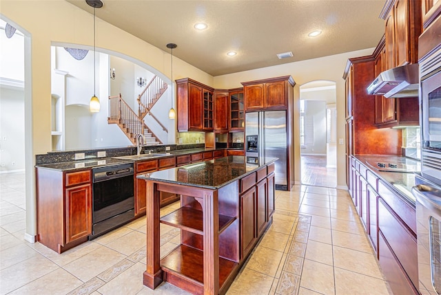 kitchen featuring black appliances, under cabinet range hood, arched walkways, and a sink