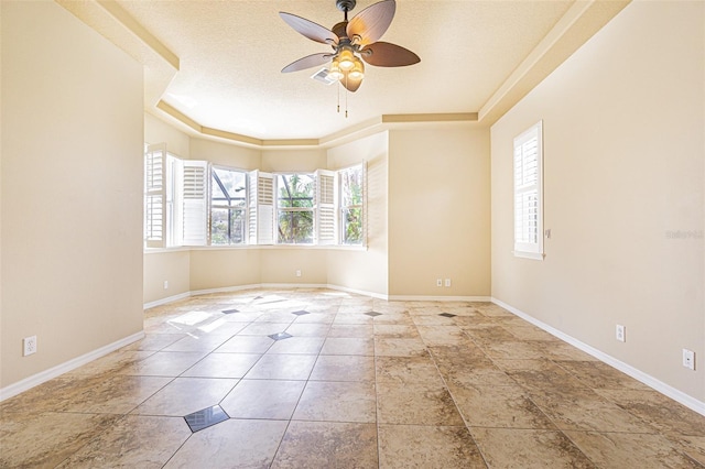 tiled empty room featuring a textured ceiling, a ceiling fan, a wealth of natural light, and baseboards