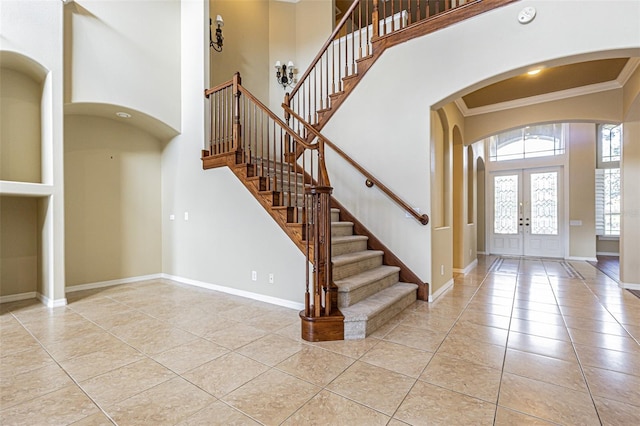 foyer with french doors, light tile patterned floors, a high ceiling, ornamental molding, and baseboards