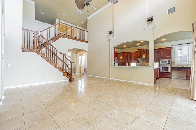 unfurnished living room with light tile patterned floors, visible vents, baseboards, arched walkways, and stairs