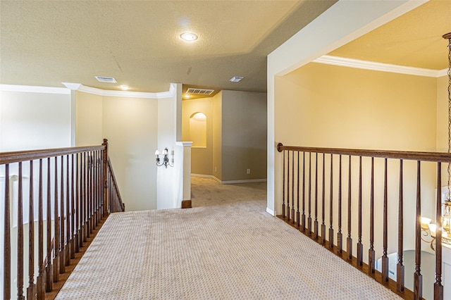 hall featuring baseboards, visible vents, crown molding, and an upstairs landing