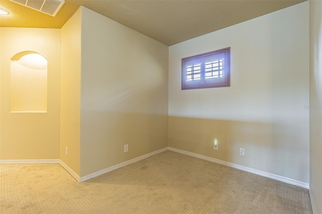 spare room featuring a textured ceiling, carpet floors, visible vents, and baseboards