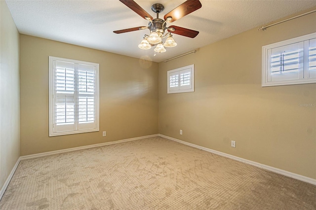 empty room featuring a ceiling fan, carpet flooring, a textured ceiling, and baseboards